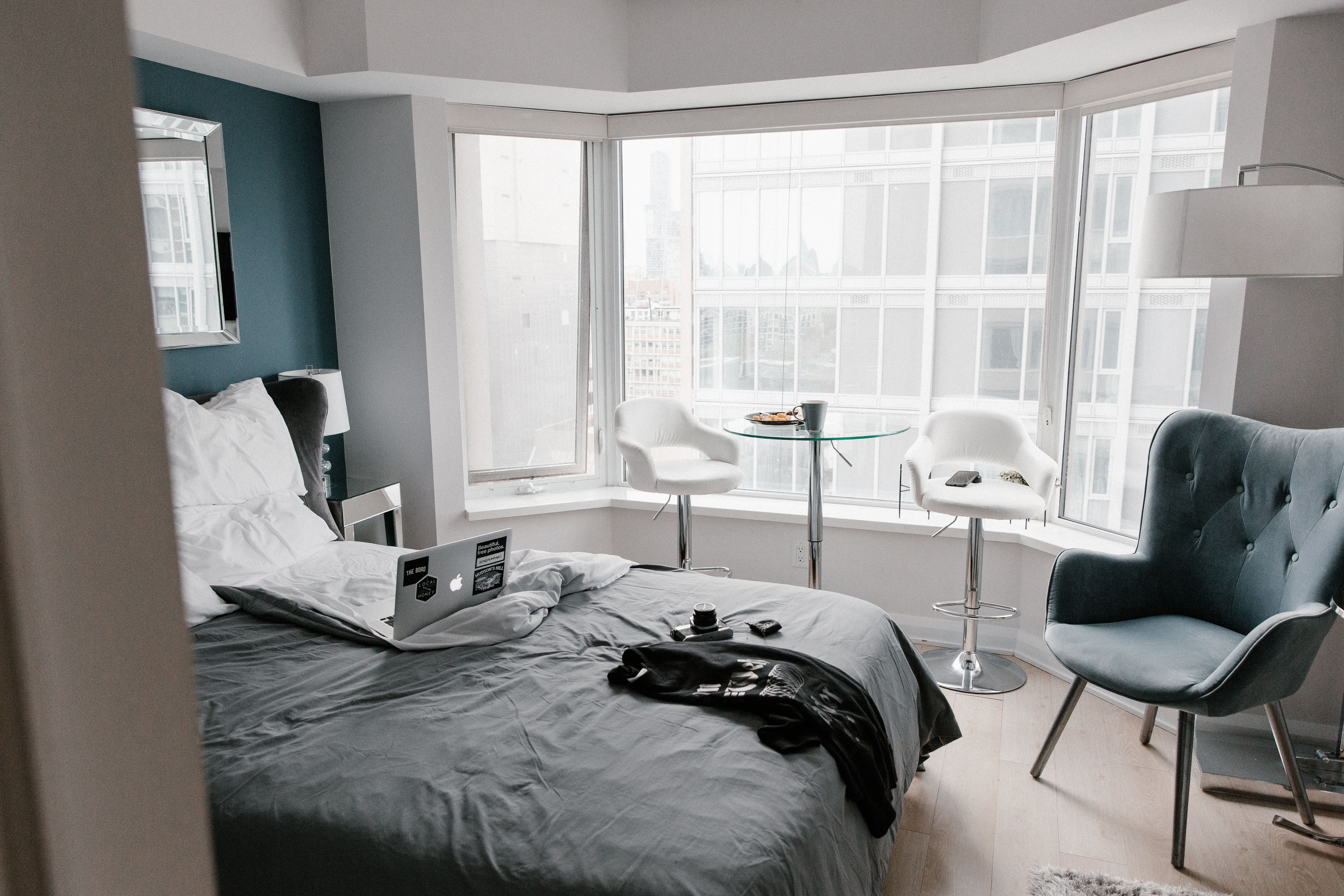 Portátil sobre una cama, junto a las ventanas de una habitación
